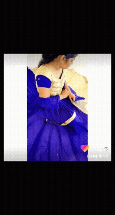 A Woman In A Blue And Gold Dress Is Sitting On A Bed . GIF