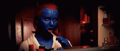 A Woman In A Blue And Red Costume Is Brushing Her Teeth In Front Of A Mirror . GIF