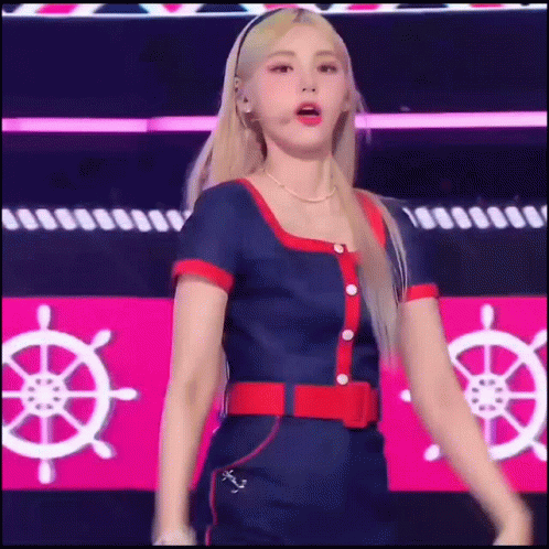 A Woman In A Blue And Red Outfit Is Dancing On A Stage With A Steering Wheel In The Background . GIF