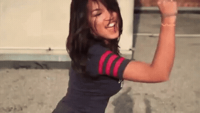 A Woman In A Blue And Red Striped Shirt Is Dancing And Making A Funny Face . GIF