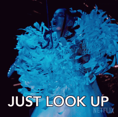 A Woman In A Blue And White Feathered Dress Is Screaming And Says Just Look Up Netflix . GIF