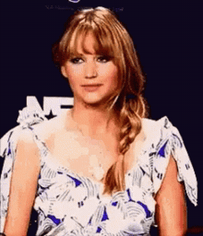 A Woman In A Blue And White Floral Dress Is Sitting In Front Of A Blue Background . GIF