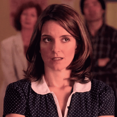 A Woman In A Blue And White Polka Dot Shirt Is Looking At The Camera GIF