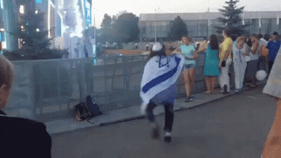 A Woman In A Blue And White Striped Shirt Is Dancing In Front Of A Crowd GIF