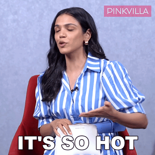 A Woman In A Blue And White Striped Shirt Is Sitting In A Red Chair And Says It 'S So Hot GIF