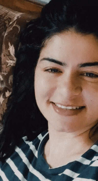 A Woman In A Blue And White Striped Shirt Smiles GIF