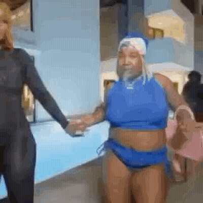 A Woman In A Blue Bathing Suit Is Holding Hands With Another Woman . GIF
