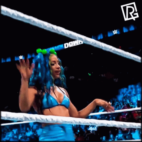 A Woman In A Blue Bikini Is Standing In A Wrestling Ring With A R On The Bottom Right GIF