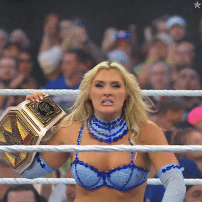 A Woman In A Blue Bra And Blue Gloves Is Holding A Wrestling Belt GIF