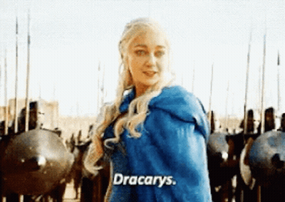 A Woman In A Blue Cape Is Standing In Front Of A Row Of Soldiers And Shields . GIF