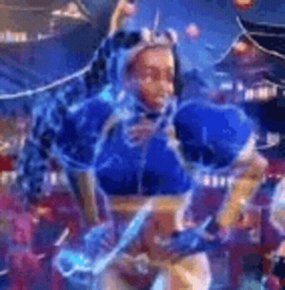 A Woman In A Blue Costume Is Dancing In Front Of A Crowd In A Video Game . GIF