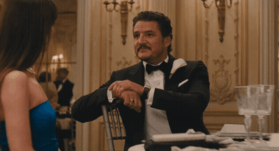 A Woman In A Blue Dress And A Man In A Suit Are Looking At Each Other GIF