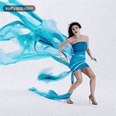 A Woman In A Blue Dress And High Heels Is Dancing With A Blue Cloth . GIF