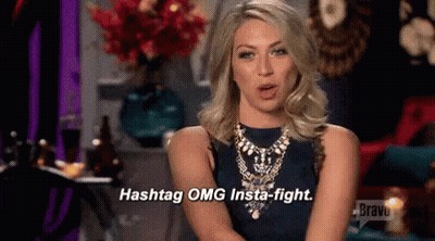 A Woman In A Blue Dress And Necklace Is Talking About Hashtags And Insta-Fights . GIF