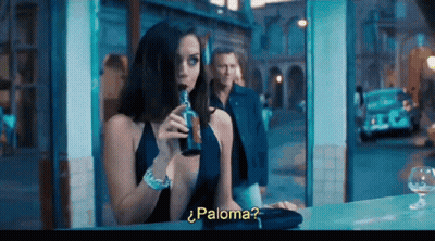 A Woman In A Blue Dress Drinking From A Bottle With The Word Paloma On The Bottom Right GIF