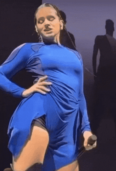 A Woman In A Blue Dress Holds A Microphone In Her Hand GIF