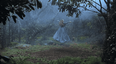 A Woman In A Blue Dress Is Dancing In A Dark Forest GIF