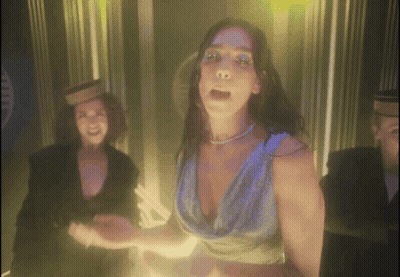 A Woman In A Blue Dress Is Dancing In Front Of A Man GIF