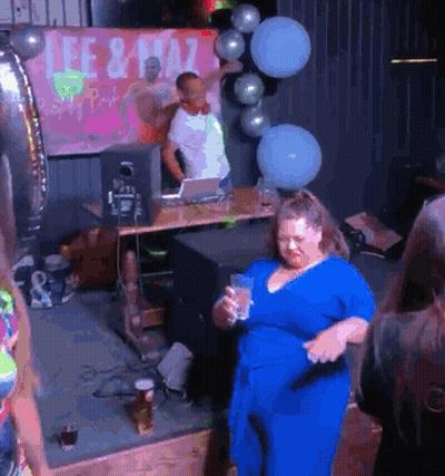 A Woman In A Blue Dress Is Dancing In Front Of A Sign That Says Lee & Plaza GIF