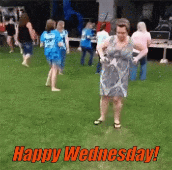 A Woman In A Blue Dress Is Dancing In The Grass With The Words Happy Wednesday Written Above Her GIF