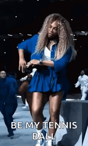 A Woman In A Blue Dress Is Dancing On A Stage And Says `` Be My Tennis Ball '' . GIF