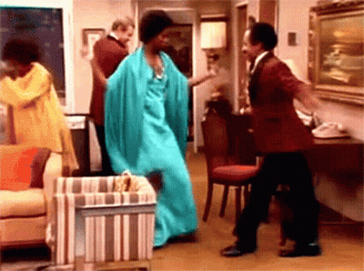 A Woman In A Blue Dress Is Dancing With Two Men In A Living Room . GIF