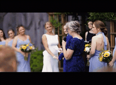 A Woman In A Blue Dress Is Giving A Speech At A Wedding GIF