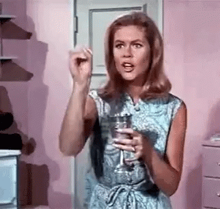 A Woman In A Blue Dress Is Holding A Glass Of Water In Her Hand . GIF