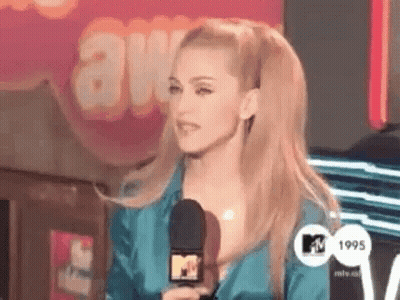 A Woman In A Blue Dress Is Holding A Microphone In Front Of A Sign That Says Awards . GIF