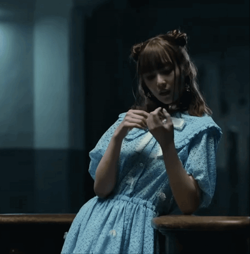 A Woman In A Blue Dress Is Holding A White Object GIF