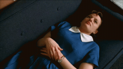A Woman In A Blue Dress Is Laying Down On A Couch GIF