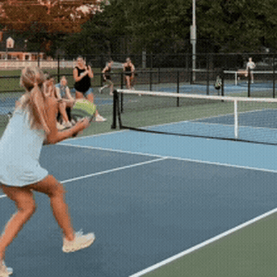A Woman In A Blue Dress Is Playing Tennis On A Tennis Court GIF