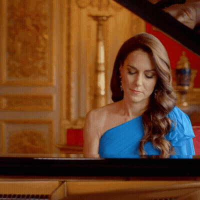 A Woman In A Blue Dress Is Playing The Piano GIF