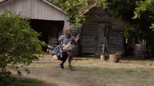 A Woman In A Blue Dress Is Running In Front Of An Old Building GIF