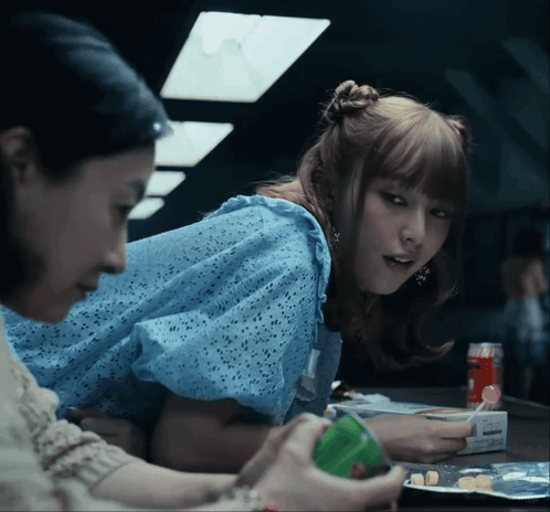 A Woman In A Blue Dress Is Sitting At A Table GIF