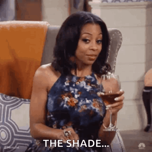 A Woman In A Blue Dress Is Sitting In A Chair Holding A Glass Of Wine . GIF