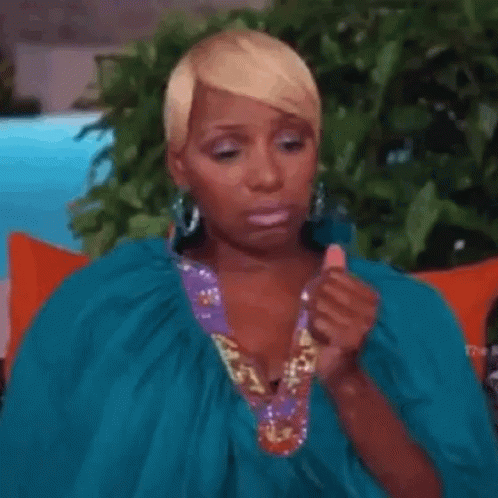 A Woman In A Blue Dress Is Sitting On A Couch . GIF