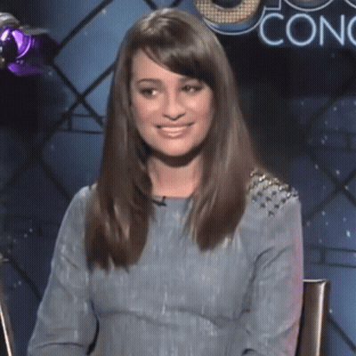 A Woman In A Blue Dress Is Smiling In Front Of A Sign That Says Conc GIF