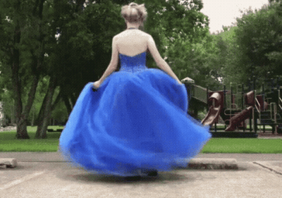 A Woman In A Blue Dress Is Spinning In Front Of A Playground .. GIF