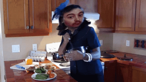 A Woman In A Blue Dress Is Standing In A Kitchen GIF