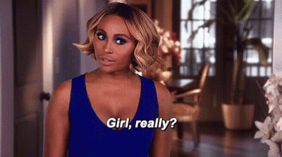 A Woman In A Blue Dress Is Standing In A Living Room Talking To Someone . GIF