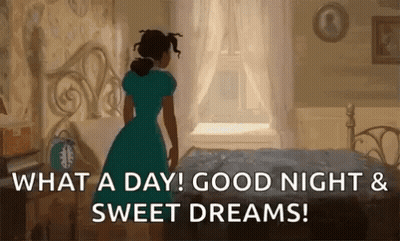 A Woman In A Blue Dress Is Standing In Front Of A Bed In A Bedroom And Looking Out The Window . GIF