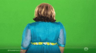 A Woman In A Blue Dress Is Standing In Front Of A Green Screen With Her Hands Outstretched . GIF