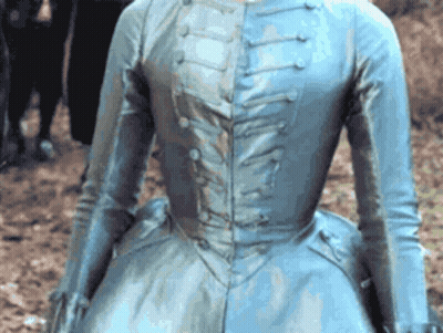 A Woman In A Blue Dress Is Standing In The Dirt GIF