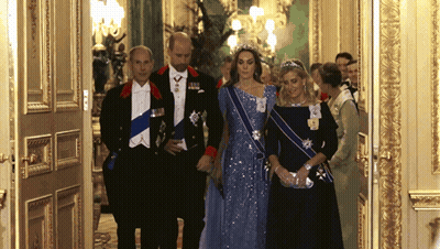 A Woman In A Blue Dress Is Standing Next To A Man In A Tuxedo And A Woman In A Black Dress GIF