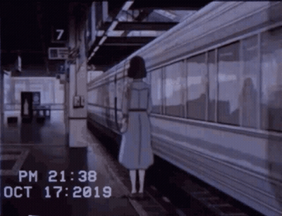 A Woman In A Blue Dress Is Standing On A Train Platform . GIF