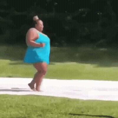 A Woman In A Blue Dress Is Walking Barefoot On A White Surface . GIF
