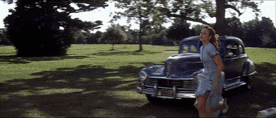 A Woman In A Blue Dress Is Walking In Front Of A Car With A License Plate That Says Jcj - 88 GIF