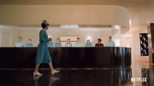 A Woman In A Blue Dress Is Walking In Front Of A Netflix Ad GIF