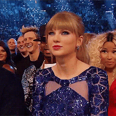 A Woman In A Blue Dress Stands In Front Of A Crowd Of People . GIF